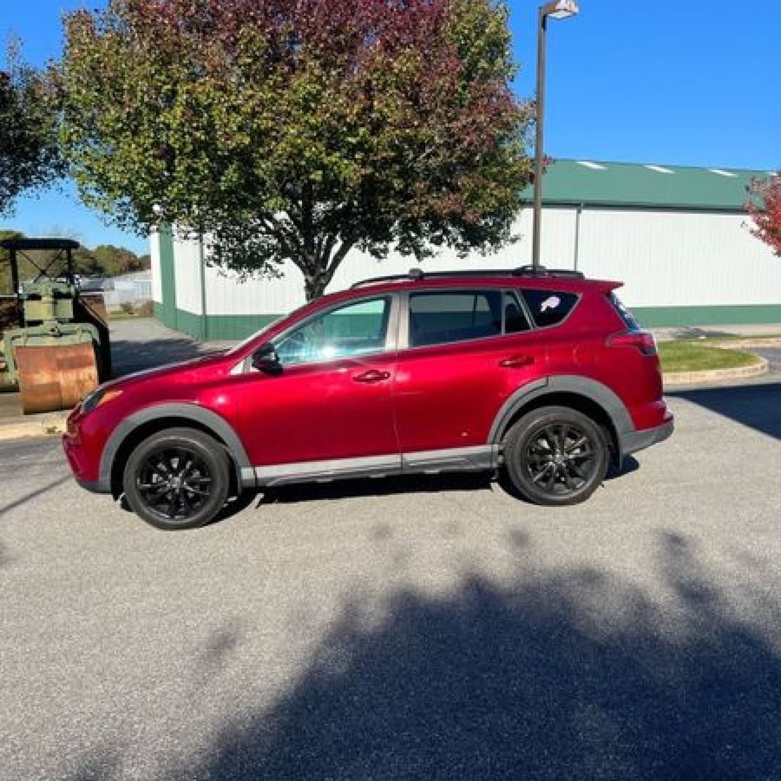 Red 2018 Toyota RAV4 parked in front of autumn trees