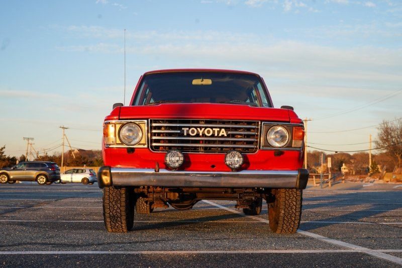 Red Toyota Land Cruiser FJ60 facing the camera at sunset